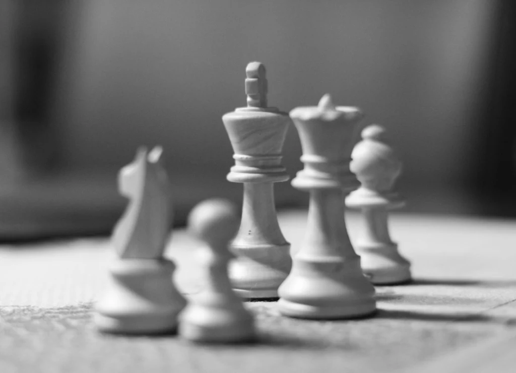 A black and white picture of chess pieces including a king, queen, knight, bishop, and pawn.